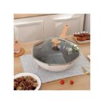 Poêle wok octogonale blanche couverte de son couvercle en verre sur une table